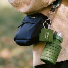 a person wearing a coat and holding a green cup with a chain attached to it