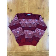 a red and white sweater sitting on top of a wooden floor