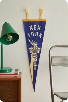 a blue and yellow pennant hanging on the wall next to a chair with a lamp