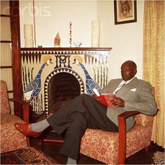 a man sitting in a chair with his feet up on the floor next to a fire place