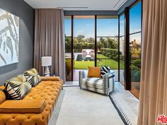 a living room filled with lots of furniture next to a large glass window covered in curtains