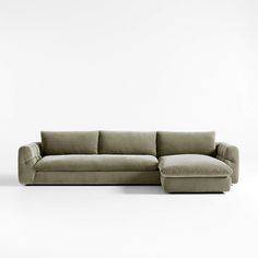 an l shaped couch with a footstool in front of a white wall and floor