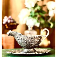 an ornate silver bowl sitting on top of a green table