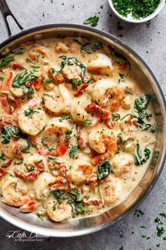 a pan filled with shrimp and spinach on top of a gray counter next to two bowls