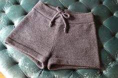 a pair of gray shorts sitting on top of a green velvet chair next to a wooden table