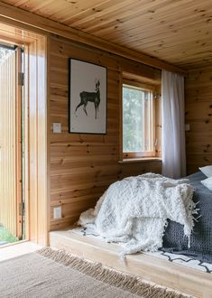 a bedroom with wood paneling and a bed covered in blankets on top of it