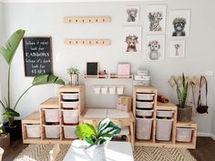 a living room filled with lots of furniture and plants on top of wooden crates in front of a white wall