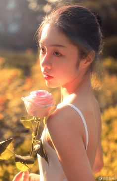 a young woman holding a rose in her hand