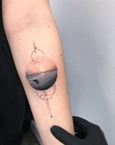 a person with a tattoo on their arm is holding a black object in the air