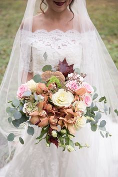 a bride holding a bouquet of flowers in her wedding dress with the veil pulled back