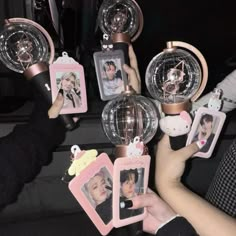 several people holding up small ornaments with photos on them in the shape of globes