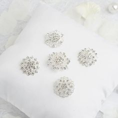 four pieces of brooch and earring set on a white pillow with flowers in the background