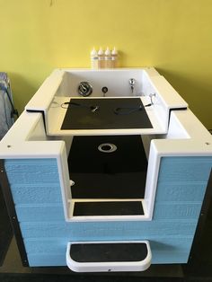 a blue and white bath tub sitting on top of a black counter next to a yellow wall