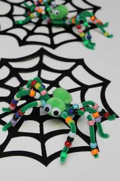 two spider toys sitting on top of a web covered in beads and sprinkles