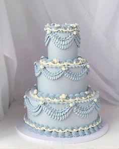 a three tiered blue wedding cake with white frosting and ruffles on top