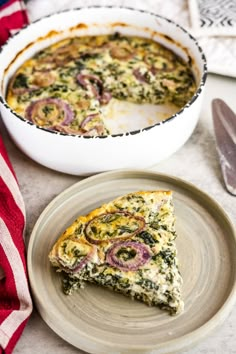 a slice of quiche on a plate next to a casserole dish with onions and spinach