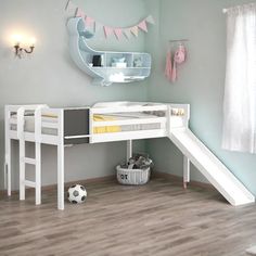 a white bunk bed sitting next to a desk with a soccer ball on top of it