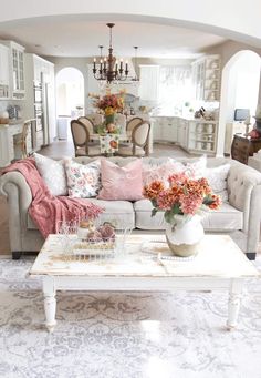 a living room filled with lots of furniture and flowers on top of a coffee table