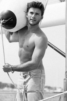 a shirtless man holding a life preserver on top of a boat