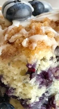 a close up of a piece of cake with blueberries and cream frosting on it