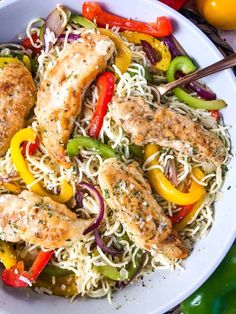 a white bowl filled with chicken, peppers and noodles next to some sliced oranges