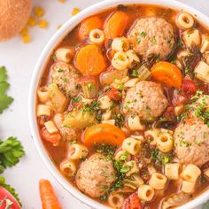 a white bowl filled with meatball soup next to carrots