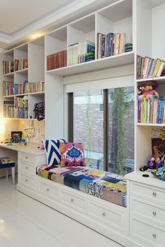 a room that has some bookshelves and a bed in it with colorful pillows