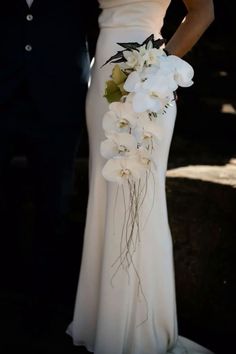 a bride and groom standing next to each other in front of the camera with white flowers