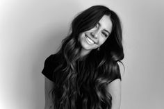 a woman with long hair is smiling and posing for the camera in black and white