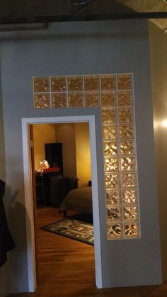 an open door leading to a bedroom with a bed in the background and lights on