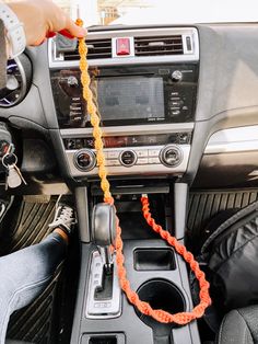 someone is holding a rope attached to the steering wheel of a car with an orange cord