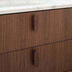 a bathroom vanity with marble top and wooden drawers