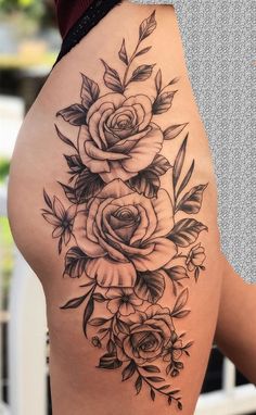 a woman's thigh with roses and leaves tattoo on the side of her thighs