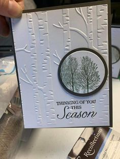 someone holding up a card that says thinking of you this season with trees on it