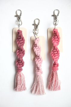 three pink and white key chains with tassels