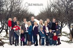 a group of people standing in the snow with trees behind them and one person holding a child