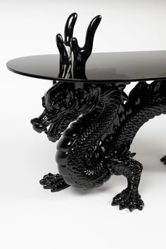 a glass table topped with a black dragon figurine