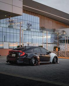 a car parked in front of a large building with glass windows on it's sides