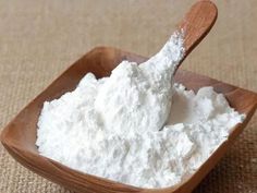 a wooden spoon filled with white powder on top of a table