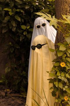 a fake ghost with sunglasses on it's face is standing next to a tree