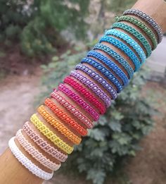 a close up of a person's arm with many different bracelets on it