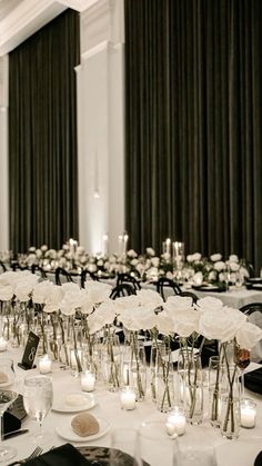 the tables are set with white flowers and candles for an elegant wedding reception in black and white