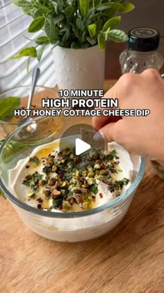 a person is adding toppings to a bowl of food on a wooden counter top