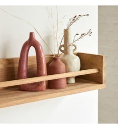 three vases and a wooden shelf on a wall