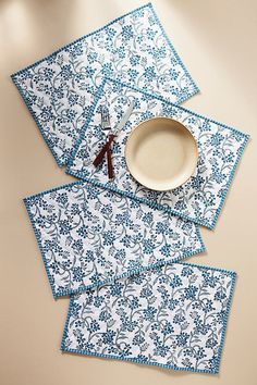 four place mats with blue and white designs on them, one has a fork in the middle