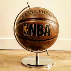 a basketball sitting on top of a metal stand in front of a white wall and wooden floor