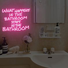 a bathroom with a neon sign that says what happens in the bathroom stays in the bathroom