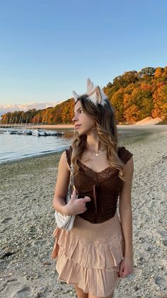 a woman standing on top of a sandy beach next to the ocean wearing bunny ears