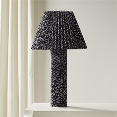 a black lamp sitting on top of a white shelf next to a curtained window