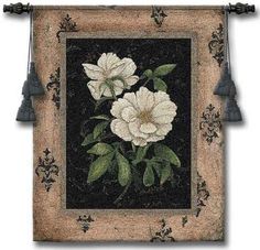 an embroidered wall hanging with white flowers and green leaves on black ground, decorated with tassels